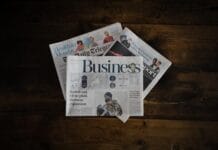 Guide to Bringing Legacy Media Into the Age of Innovation A stack of business newspapers on a wooden surface.