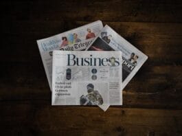A stack of business newspapers on a wooden surface.