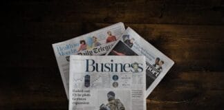 A stack of business newspapers on a wooden surface.