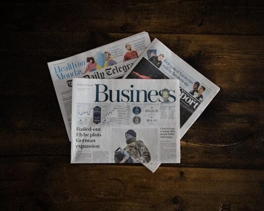 A stack of business newspapers on a wooden surface.