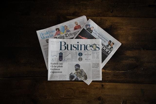 A stack of business newspapers on a wooden surface. 
