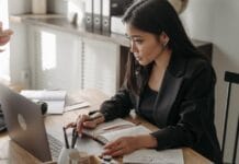 A professional engaged in online learning at a laptop with a notebook