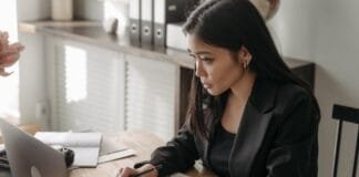 A professional engaged in online learning at a laptop with a notebook