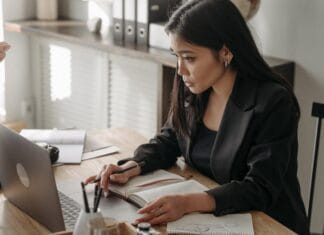 A professional engaged in online learning at a laptop with a notebook