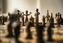 Antique bronze chess pieces arranged on a board.