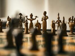 Antique bronze chess pieces arranged on a board.