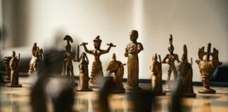 Leadership Strategies for Creating Meaningful Community Impact Antique bronze chess pieces arranged on a board.