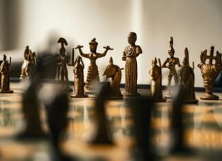 Antique bronze chess pieces arranged on a board.