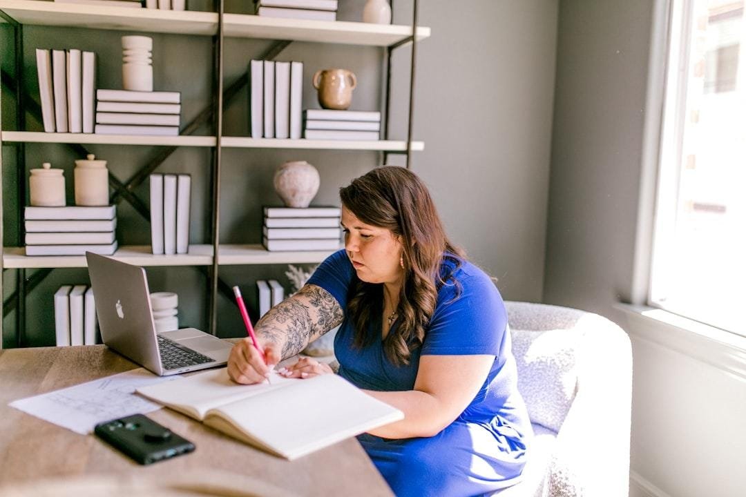 Independent consultant working at a desk with a laptop and a notebook in a home office